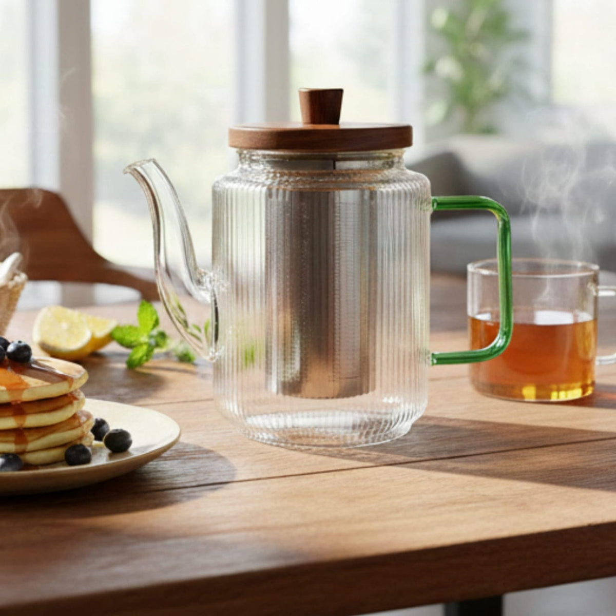Glazen theepot met thee naast een ontbijt op een houten tafel