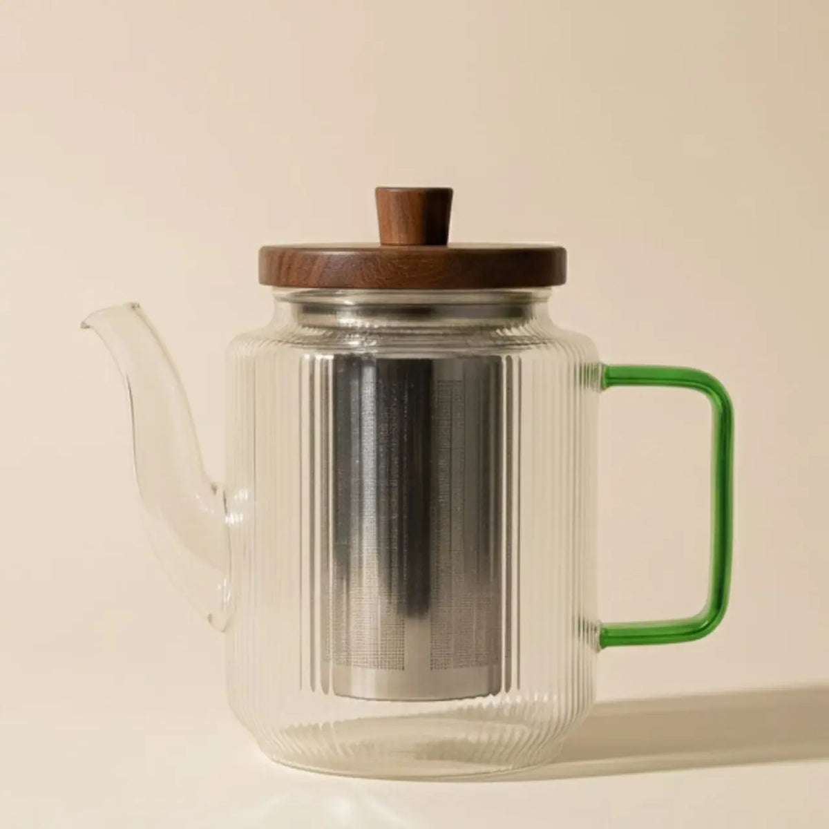 Glazen theepot met jadegroen handvat op een lichte achtergrond