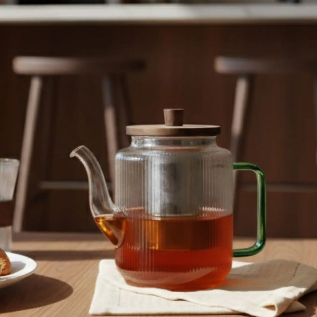 Glazen theepot gevuld met thee op een houten tafel