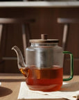 Glazen theepot gevuld met thee op een houten tafel
